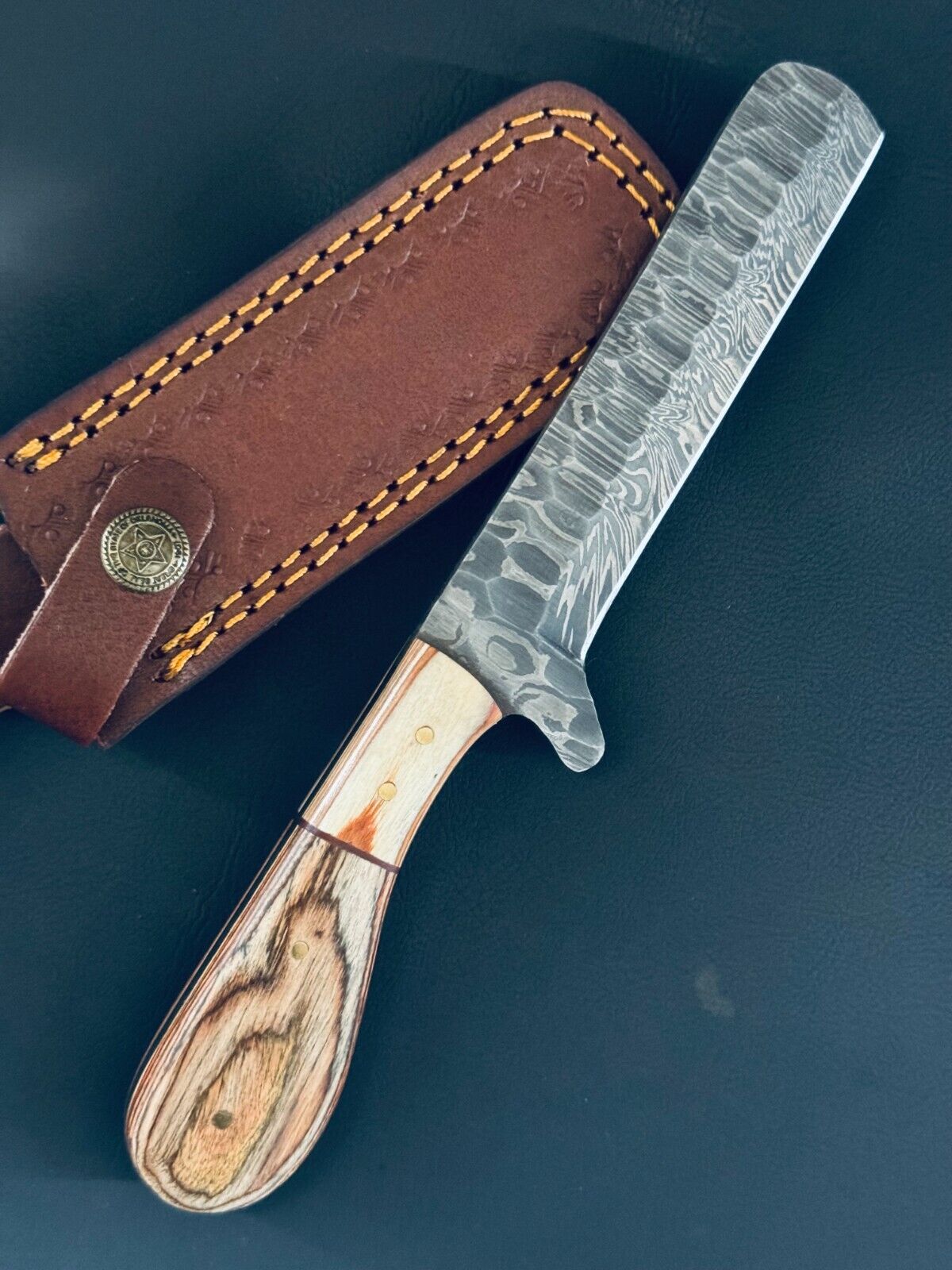 Cowboy bull cutter knife featuring a pakkawood handle and a Damascus steel blade.