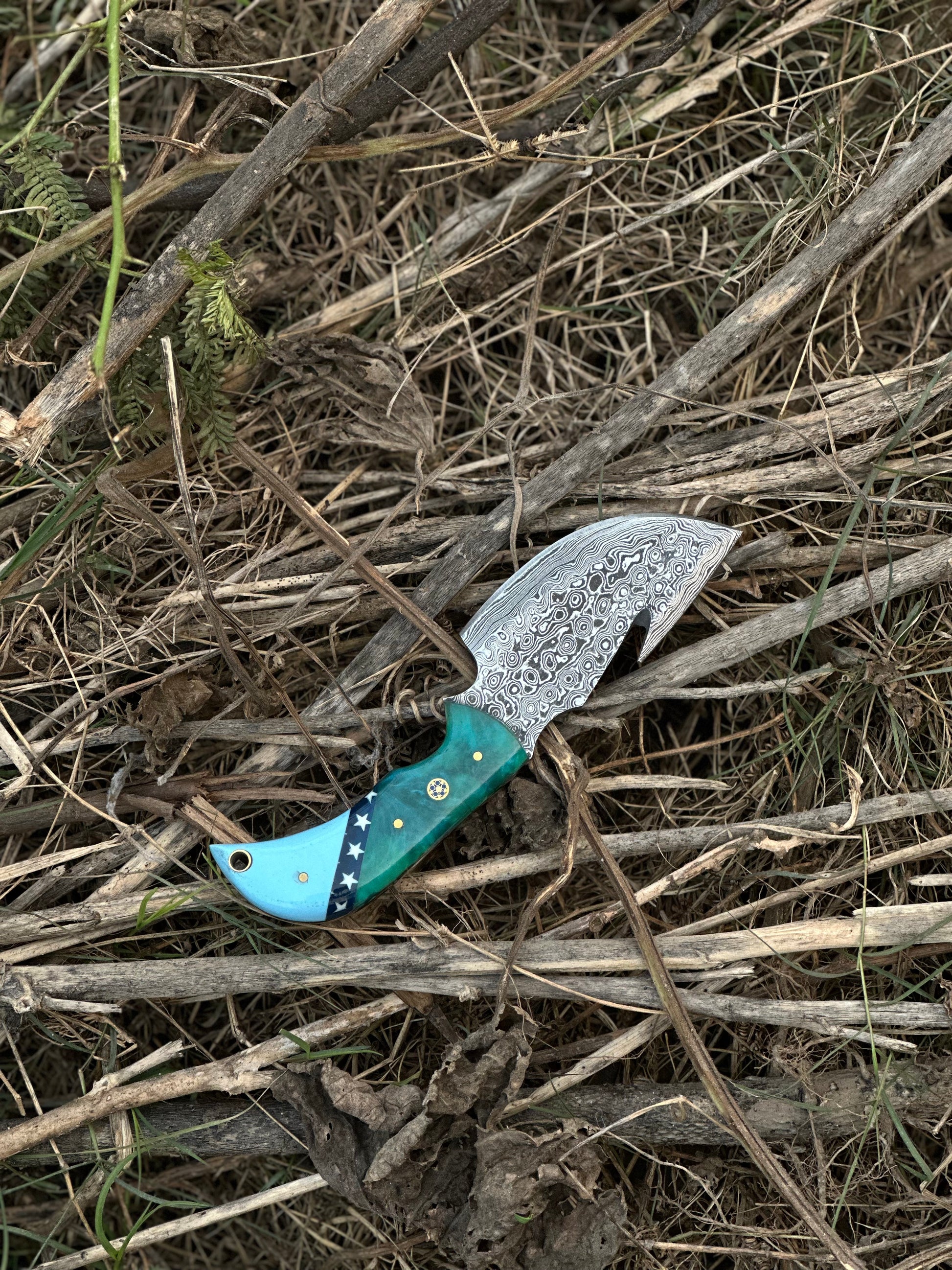 7.5” Damascus steel guthook knife featuring a high-end resin handle, with a premium leather sheath.