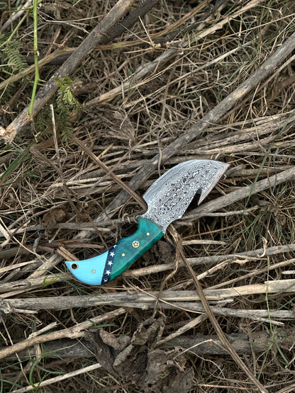 7.5” Damascus steel guthook knife featuring a high-end resin handle, with a premium leather sheath.
