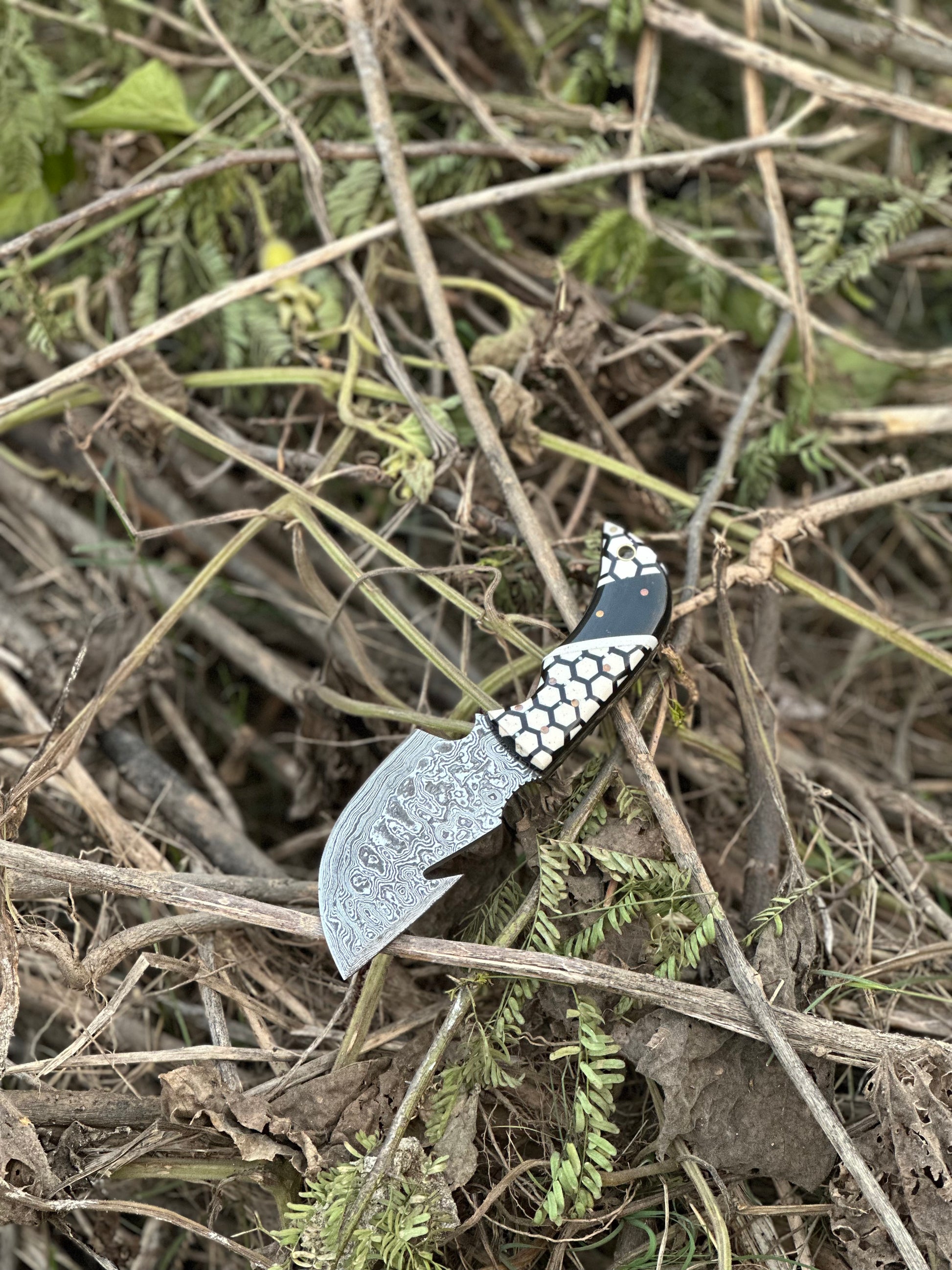 7.5” Damascus steel guthook knife with a one-of-a-kind resin handle and bespoke leather sheath.