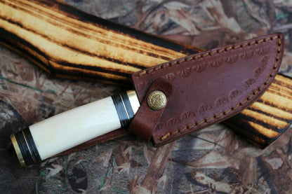 "Close-up of camping knife featuring a camel bone handle and brass guard."
