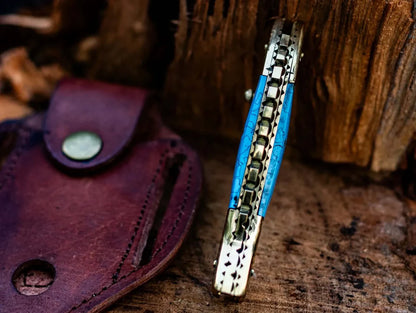Custom Damascus steel folding knife with fish design, epoxy resin handle, and brass accents, including a leather sheath