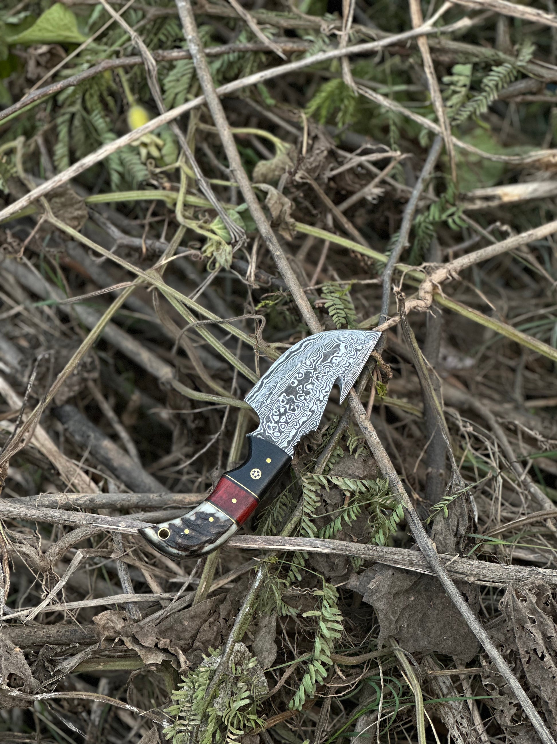 Custom Damascus steel guthook knife with a durable resin handle, ideal for skinning, with a leather sheath