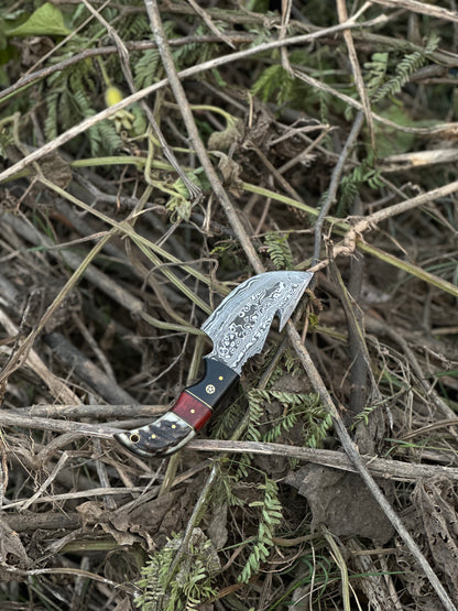 Custom Damascus steel guthook knife with a durable resin handle, ideal for skinning, with a leather sheath