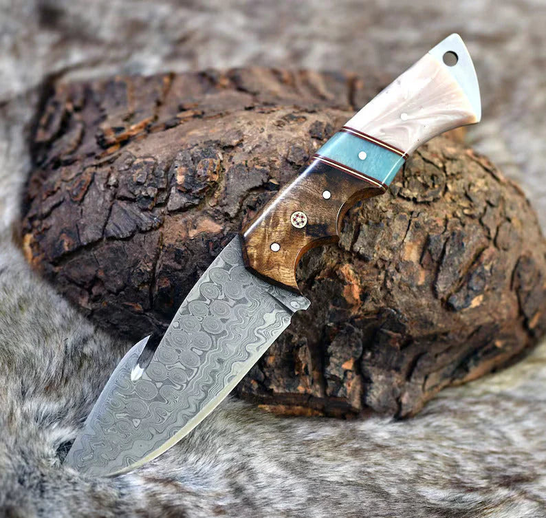 Custom Raindrops Damascus steel gut hook knife featuring a rosewood and epoxy resin handle, complete with a handcrafted leather sheath.