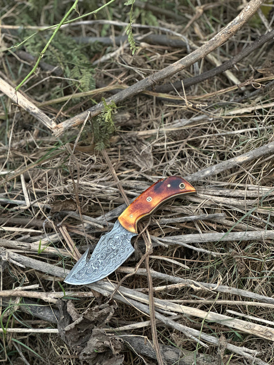 Custom handmade Damascus steel guthook knife with camel bone handle and leather sheath.