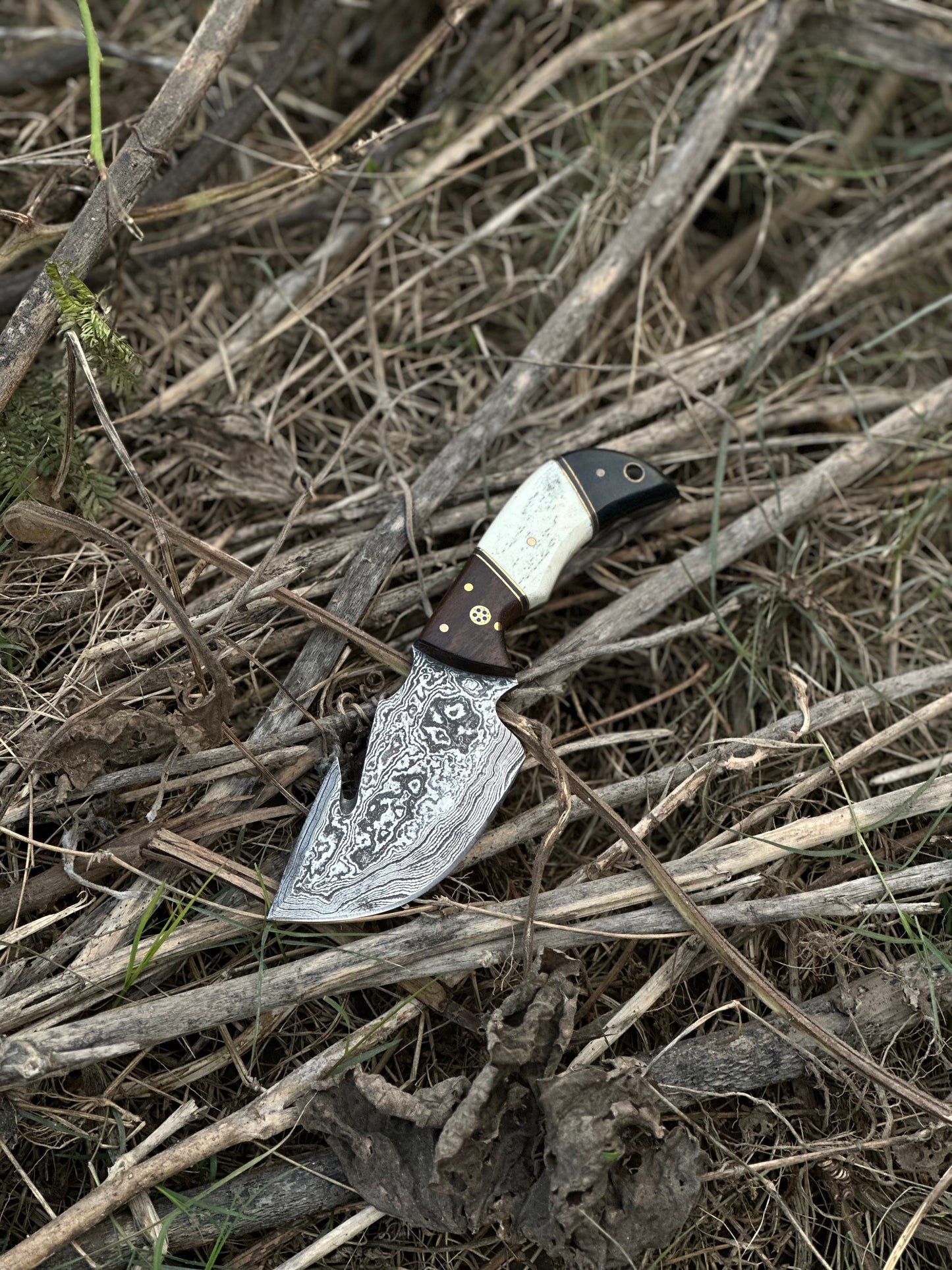 Custom handmade Damascus steel guthook skinning knife with rosewood, camel bone, and black sheet handle, paired with a leather sheath.