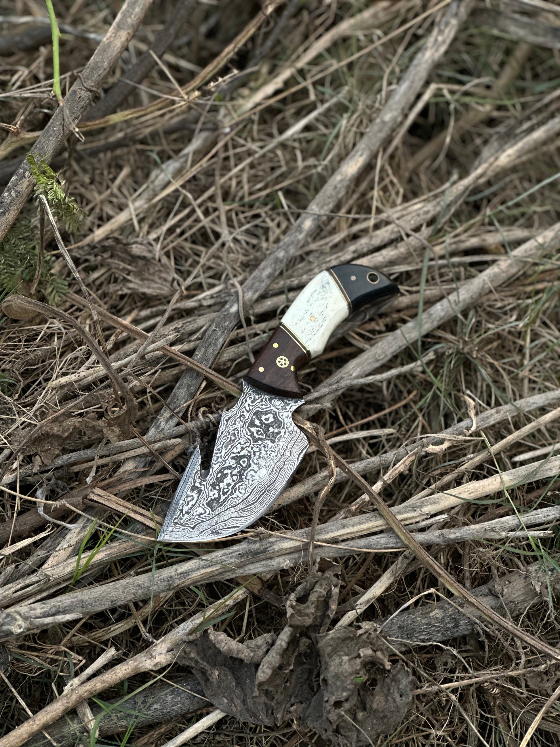 Custom handmade Damascus steel guthook skinning knife with rosewood, camel bone, and black sheet handle, paired with a leather sheath.