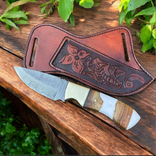 Custom handmade Damascus steel skinning knife with a 7.75-inch blade, brass bolster, rosewood and resin handle, and a hand-engraved belt loop leather case.







