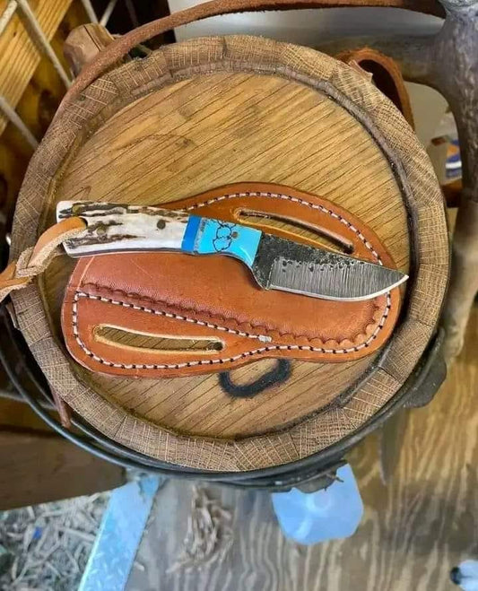 Custom handmade cowboy knife in a belt with 3.5-inch J2 steel blade, stag horn and resin handle, featuring a classic western design and belt holster for easy carrying