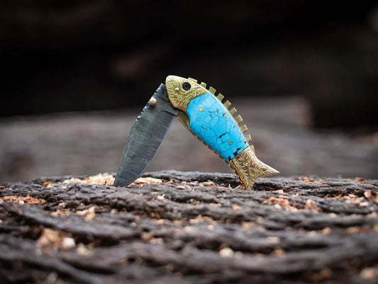 Custom handmade fish style Damascus steel folding knife with epoxy resin handle and brass accents, with a leather sheath.