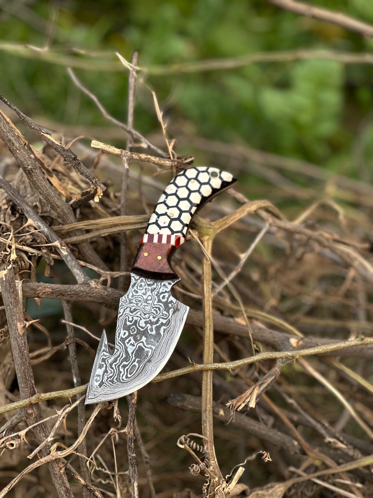 Damascus steel guthook knife featuring a rosewood and resin handle with a leather sheath