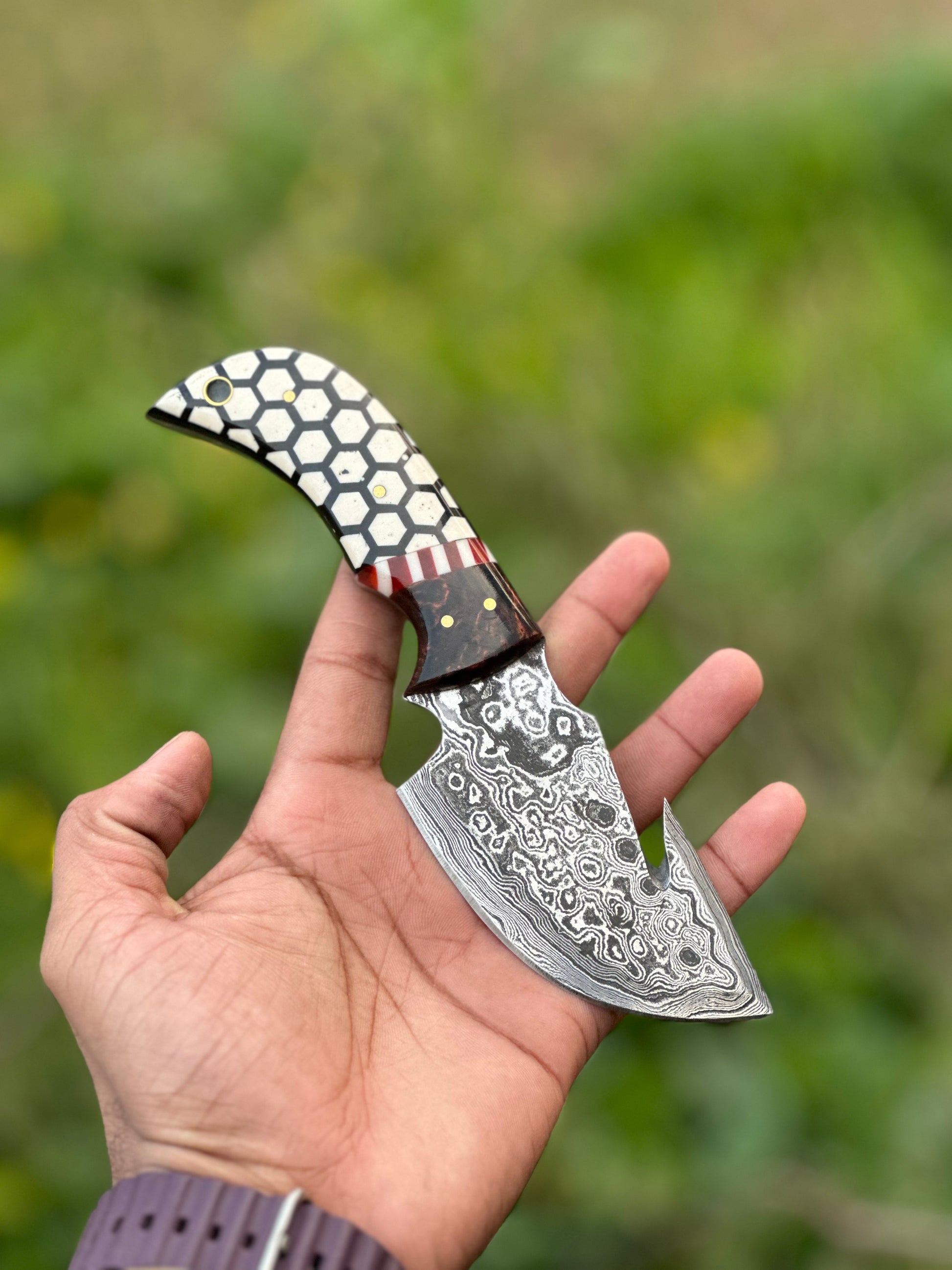 Damascus steel guthook knife with a custom rosewood and resin handle, complete with a leather sheath