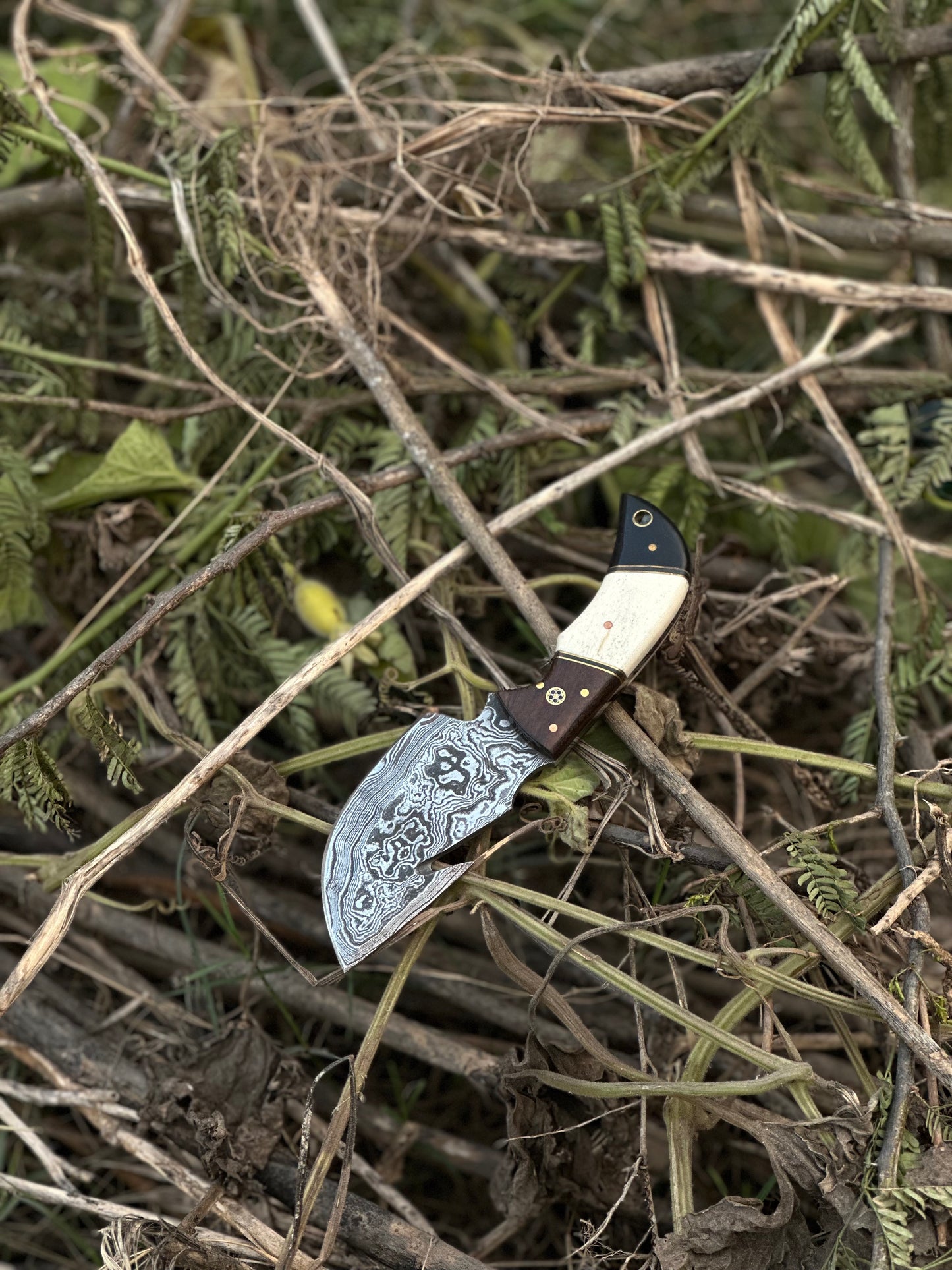 Damascus steel guthook skinning knife with a unique rosewood, camel bone, and black sheet handle, complete with a leather sheath
