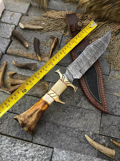 "Hand-forged Damascus steel Bowie knife featuring a 13-inch blade, bone handle, brass guard, and included leather sheath