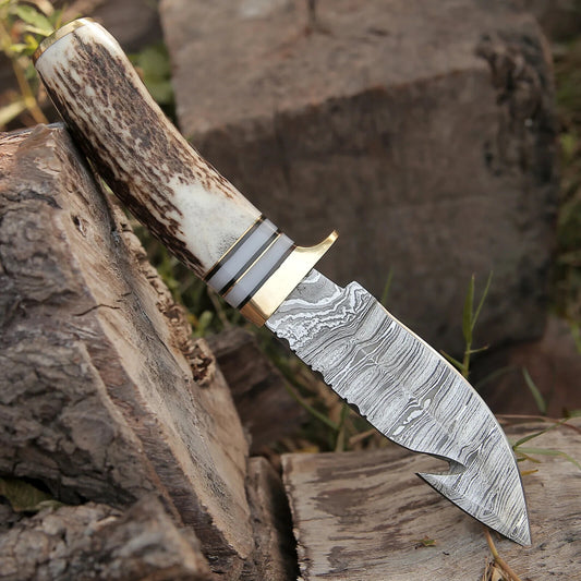 "Handcrafted guthook skinning knife featuring Damascus steel and a brass guard handle."
