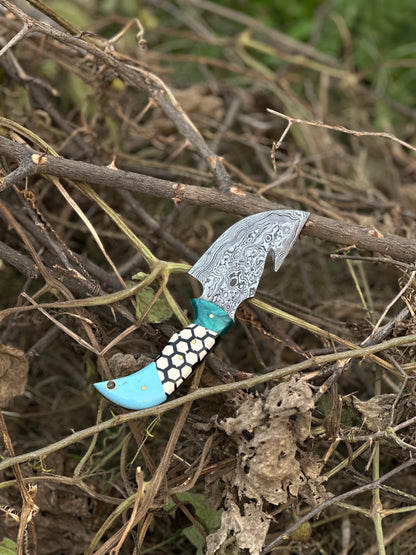 Handmade Damascus steel guthook skinning knife with a resin handle and leather sheath.