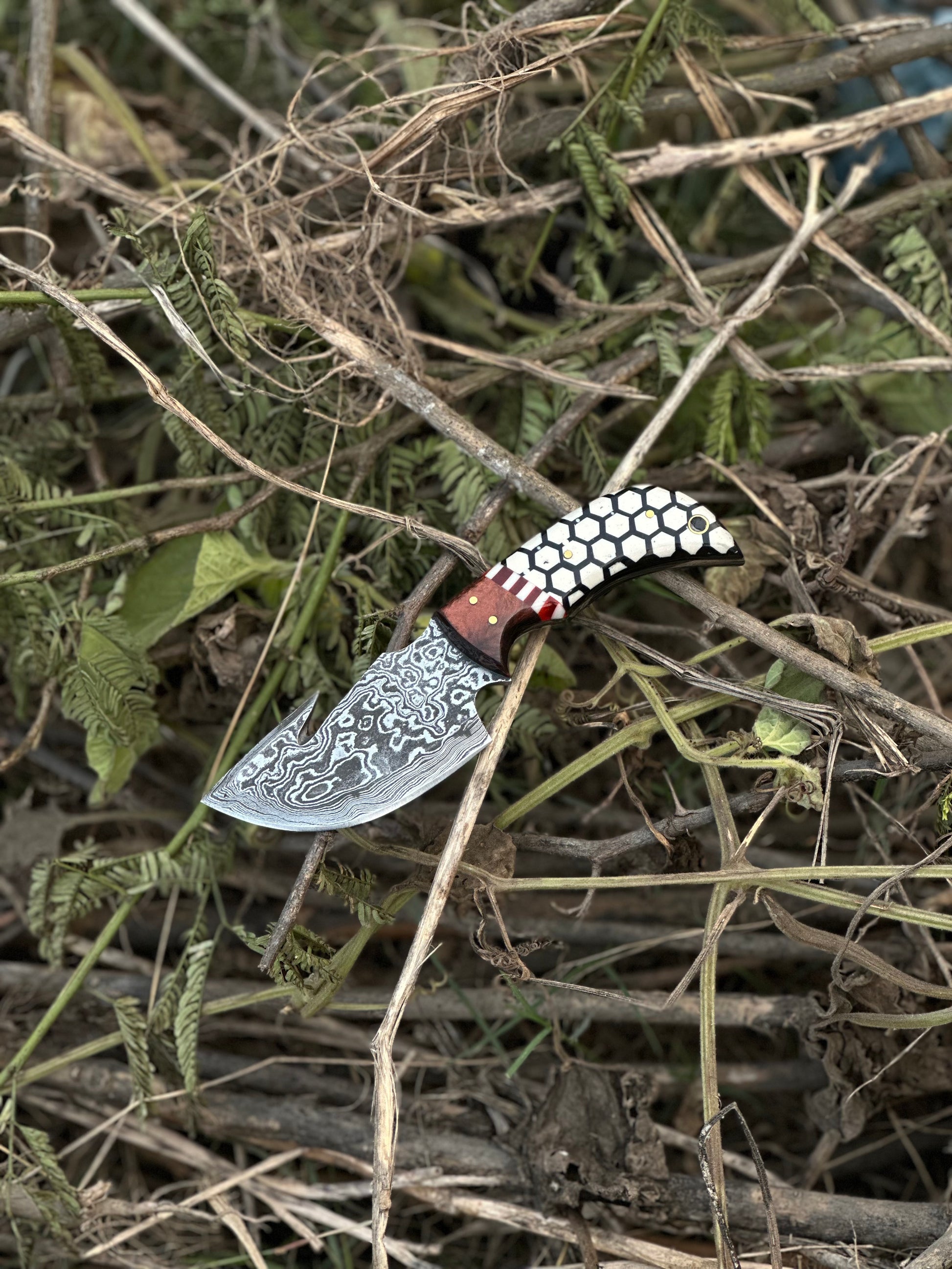 Handmade Damascus steel skinning knife with guthook design, rosewood and resin handle, and leather sheath