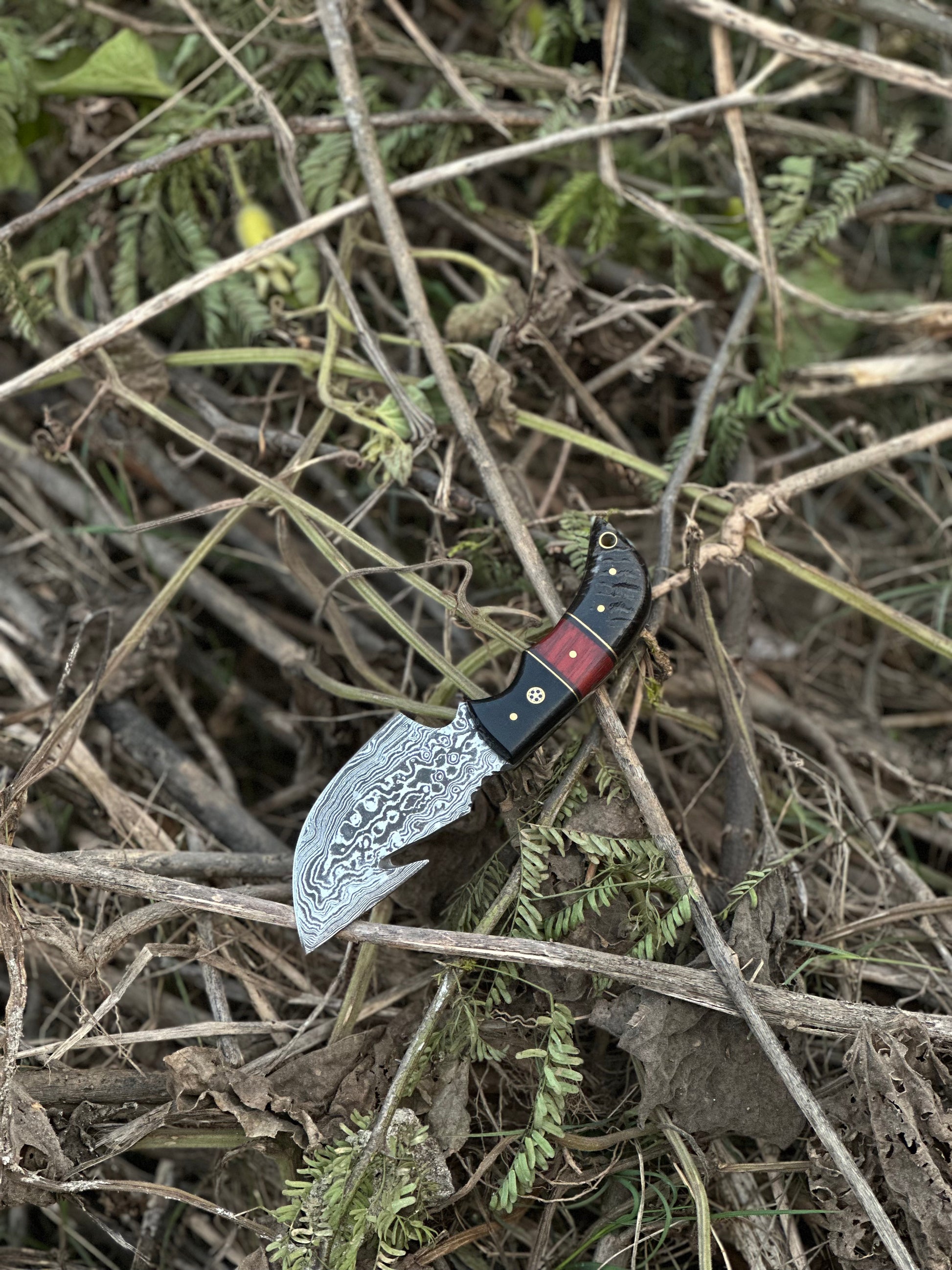 Superior Damascus steel guthook knife featuring a resin handle, paired with a handcrafted leather sheath