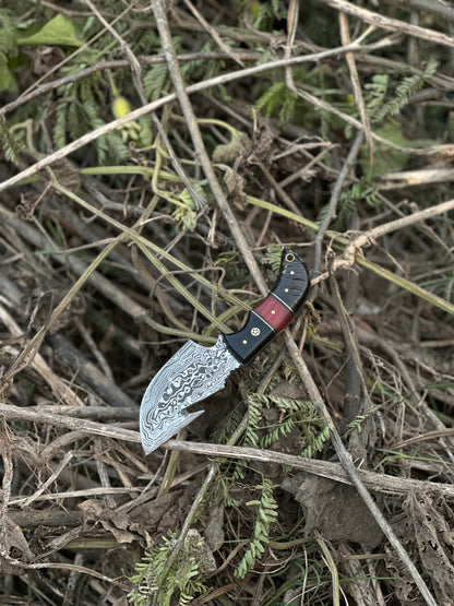 Superior Damascus steel guthook knife featuring a resin handle, paired with a handcrafted leather sheath
