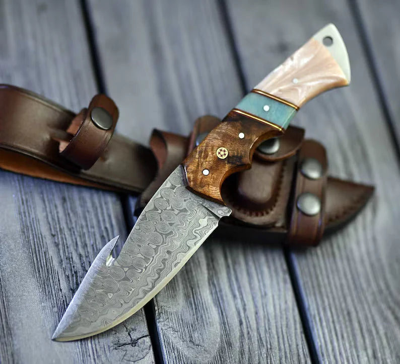 The Hunter's Edge: 8.25-inch gut hook skinning knife with Raindrops Damascus steel blade, rosewood and epoxy resin handle, and leather sheath