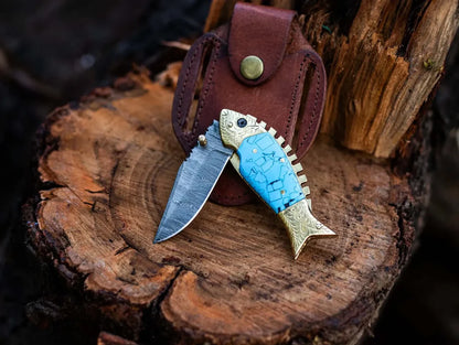 Unique fish style Damascus steel knife with an epoxy resin handle and brass accents, housed in a handcrafted leather sheath